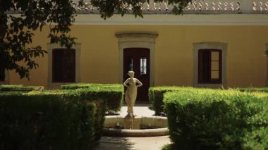 Algarve, Portekiz 2025.07.01 Sarı Akdeniz tarzı bir villanın önündeki küçük bir fıskiyeyle çevrili klasik taş heykel..