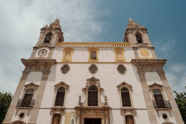 Algarve, Portekiz 2025.06.28 Barok tarzı bir kilise. İkiz çan kuleleri, süslü oymaları ve parlak mavi gökyüzüne karşı kurulmuş saat yüzleri var. 