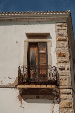 Algarve, Portekiz 2025.06.28 Süslü demiryolu ve tarihi bir binanın yıpranmış ahşap kapısı olan bir köy balkonu. 