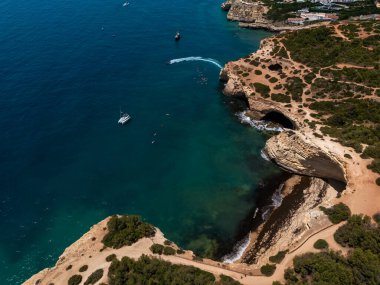 Algarve, Portekiz 2025.06.30 Benagil Mağaralarının ikonik uçurumları, turkuaz suları ve kıyı şeridini keşfeden teknelerin insansız hava aracı görüntüsü.. 