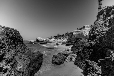 Portimo, Algarve, Portekiz 2025.07.02 Praia dos Trs Castelos 'un dramatik uçurumları, kaya oluşumları ve açık bir gökyüzü altında Atlantik Okyanusu' nun tek renkli fotoğrafı..  