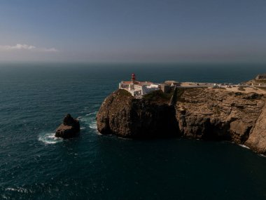 Sagres, Algarve, Portekiz 2025.07.03 Cape St. Vincent deniz fenerinin kırmızı kubbesi Atlantik Okyanusu 'nun üzerindeki engebeli kayalıklarda duruyordu.. 