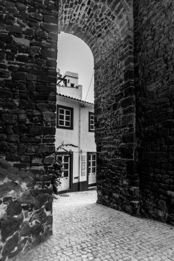 Silves, Algarve, Portekiz 2025.07.04 Monochrome manzaralı antik taş kemer yolu parke taşı caddeleri ve geleneksel beyaz boyalı evleri ortaya çıkarıyor.. 