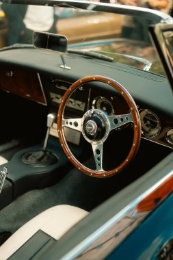 London, UK  2025.09.27  A close-up of a classic car interior featuring a polished wooden steering wheel, chrome details, and vintage dashboard at the Classic Car Boot Sale 