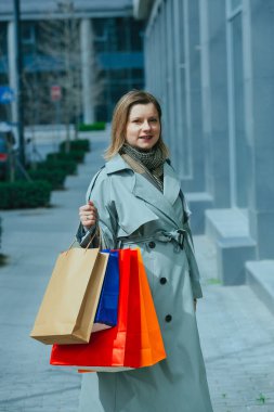 Bir sürü kağıt torbası olan mutlu bir kadın sokakta yürüyor, hafta sonları kadınlar için boş bir etkinlik, alışveriş koliği.