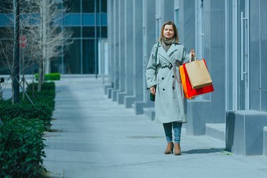 Bir sürü kağıt torbası olan mutlu bir kadın sokakta yürüyor, hafta sonları kadınlar için boş bir etkinlik, alışveriş koliği.