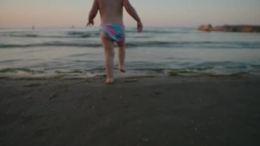 Kıyıya yakın suda oynayan tatlı bir çocuk, denizi keşfeden küçük bir çocuk. Çocuk konseptiyle güvenlik ve dikkatsizlik ve tatil