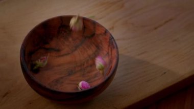 Kurumuş gül tomurcukları, yakın plan. Kurumuş gül tomurcukları bir kaseye düşer. Pembe gül tomurcukları bitkisel ilaçlar ve aromatik malzemeler olarak mutfak malzemeleri.. 