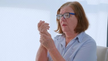 Koluna masaj yapan yaşlı bir kadın, tendonlar ve osteoporoz sorunu. Emeklinin eklemlerle sorunu var