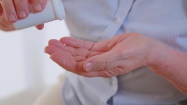 Yaşlı kadınların eline tüpten bir sürü ilaç düşerken yakın çekim, Alzheimer sendromu tedavisi. Emeklilikten sonra sağlık sorunları