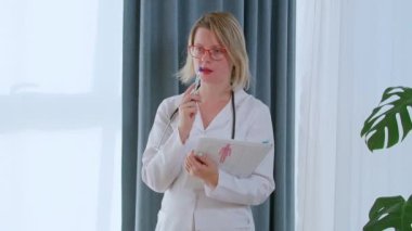 Ofisindeki kadın doktor hastayı hazırlıyor ya da teşhis ediyor. Ciddi kadın doktor analiz sonuçlarını inceler.