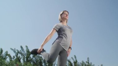 Parkta esneme egzersizleri yapan bir kadın, spor eğitimiyle güne başlıyor. Sağlıklı bir yaşam tarzınız var.