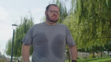 Sabah parkta koşan ve dizinde ağrı hisseden bir adam. Sağlık sorunları ve spor eğitimleri zarar verebilir ve yardımcı olabilir..