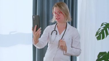 Kadın doktor hastasıyla görüntülü görüşme yapıyor. Tedavi ve reçeteyi açıklıyor. Uzaktan çalışan ve telefonla danışmanlık yapan beslenme uzmanı.