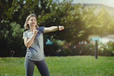 Parkta boks yapan genç bir kadın, kendine güvenen bir kadın tüm sorunlarla savaşıyor. Sağlıklı yaşam tarzı ve günlük eğitim.