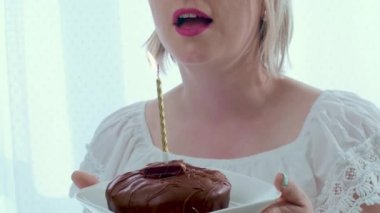 Cilalı çikolatalı çörek ve yanan mumla doğum günü temalı bir kadın. Tatillere karşı diyet ve diyabet sorunları