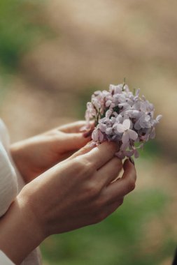 Kadın eli tarlada çiçeklerle yakın çekim, parfüm reklamı. Tatlı rüya gören kız, hayal kurmaya devam et..