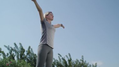 Parkta ayakta nefes egzersizi yapan bir kadın. Fitness kadını dışarıda ayakta derin bir nefes alıyor, fiziksel egzersizlere hazırlanıyor. Yüksek kalite 4k görüntü