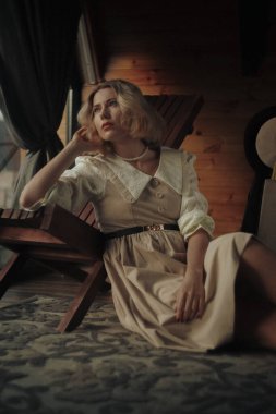 Evde pencerenin yanında oturan bir kadın, kötü ruh hali, akıl sağlığı sorunları. Orman evinde sessiz bir yer, yalnız kalma ve olayları çözme zamanı.