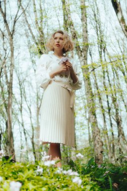 Ormanda bahar çiçekleriyle gezen güzel bir kadın. Tatilde boş zaman aktivitesi. Ormanda rüya gören kız