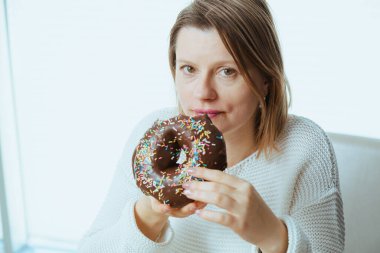 Açlık çeken, çikolatalı donut yiyen, diyet temalı bir kadın. Yeme problemi ve şeker bağımlılığı yüzünden.