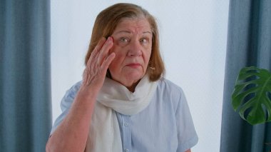 Yaşlı bir kadın yüzüne dokundu ve kaç tane kırışıklığı olduğunu değerlendirdi. Emeklilikten sonra yaşlanma süreci, tekrar güzel olmak için ameliyata hazırlanma. 