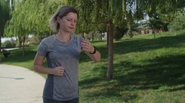 Parkta koşan bir kadına yaklaşmak spor egzersizlerini seven insanlar için harika bir başlangıç. Pozitif duyguları olan kendine güvenen genç bir kadın.