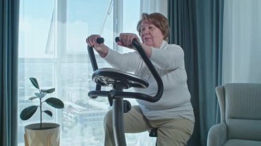 Evde bisiklet eğitmeni eğitimi alan yaşlı bir kadın. Emeklilikten sonra sağlıklı bir yaşam tarzı.. 