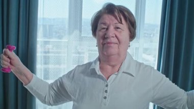 Kıdemli kadın, egzersiz, güç kondisyonu ya da egzersiz için ev ve halterler. Kadın, ağırlık ve oturma odası, sağlık hedefleri için mutluluk, spor yapmaya bağlılık ya da gülümseyerek sağlık. Yüksek kalite 4k görüntü