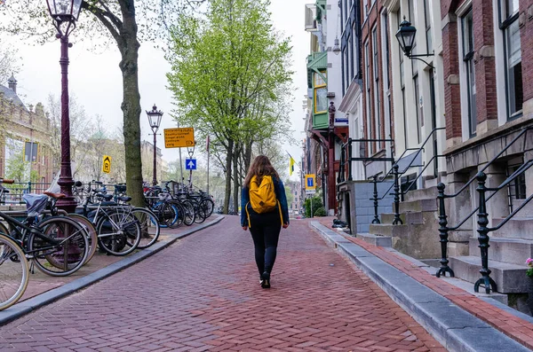 アムステルダムの街を歩く黄色のバックパックを持つ女性 — ストック写真