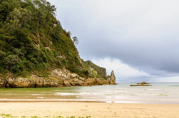砂浜と岩の多い丘が海に出ます — ストック写真