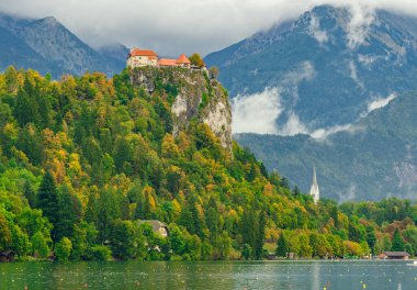 Slovenya 'da bir şatonun sabah fotoğrafı - Bled Gölü. Ormanın ortasındaki bir tepenin üstüne yerleştirilmiş. Güzel peri masalı bulutlu puslu manzara.