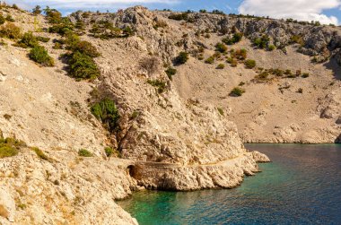 Deniz kıyısındaki bir yolda taş köprü. Sarı taştan dağların ortasında. Mükemmel yüzme yeri..