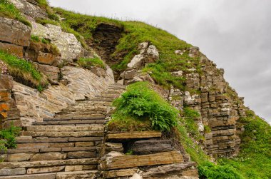 İskoçya 'daki Sinclair Girnigoe Kalesi' ndeki merdivenlerin detayları. Kaya yüzgeci üzerine inşa edilmiş güzel bir taş yapı. Bulutlu hava.