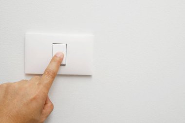 Turn off the light, close up female hand is closing the power switch. Save energy, reduce global warming.	