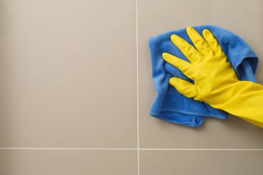Ev hanımı banyo duvarını temizlemek için bez kullanıyor..