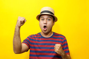 Hipster 'lı genç adam portresi. Sıradan bir genç adam. Kırmızı çizgili tişört ve şapka takıyor. Hareketli duygular kolları genişletiyor stüdyo portrelerinde utangaç, sarı arka plan..