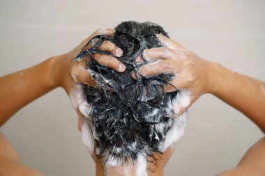 Bir adam saçını şampuanla yıkıyor.