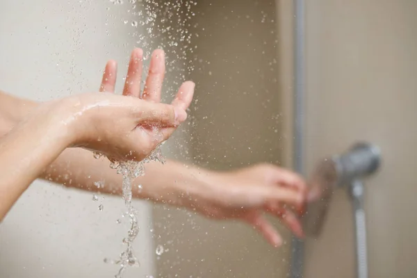 一个女人在洗澡前用手测量热水器的水温 — 图库照片