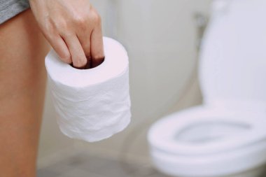 Evdeki tuvalette dışkılayan bir kadın.