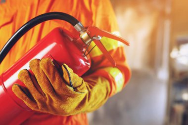 Yangın söndürücüye el basınca yangın söndürücü kullanılabilir durumda. Acil durum yangın hasarı arka planında. Güvenlik.
