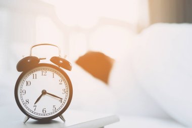 Yatakta uzanmış, elini kapatmış, çalar saat rengine uzanmış siyah bir adam. Sabah 7: 20 'de uyanır..