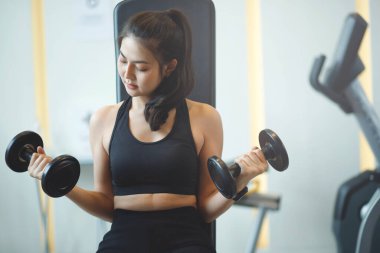 Spor salonunda kilo vermek için halterleri kaldıran Asyalı kadın.