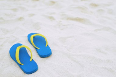 Sahilde deniz, kumsalda ayak izleri, kumsalda ayak izleri ve sandaletlerin terlikleri. seyahat tatili kavramı.