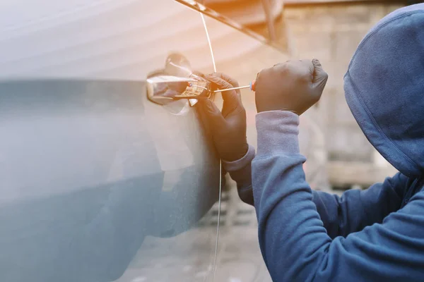 stock image Close up car thief hand holding screwdriver tamper yank and glove black stealing automobile trying door handle to see if vehicle is unlocked  trying to break into inside. 