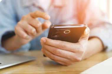 Genç adam ekose gömlek giyer. kanepe üzerinde dinlenme sırasında cep telefonu kullanarak el yakın. mola sırasında cep telefonu ile mesaj izlerken rahatlayın. yumuşak odak.