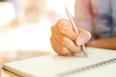 yakın yukarı el genç adam masa ahşap kitap içine kayıt ders notu Pad yazma kullanarak oturuyor.