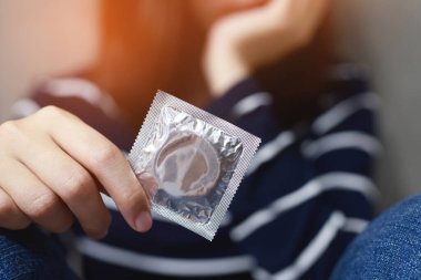 Prezervatif kadın elinde kullanıma hazır, yatakta prezervatif güvenli seks konsepti vermek Enfeksiyon önlemek ve Kontraseptifler doğum oranı veya güvenli profilaktik kontrol. Dünya Aids Günü, Metin için yer bırak.