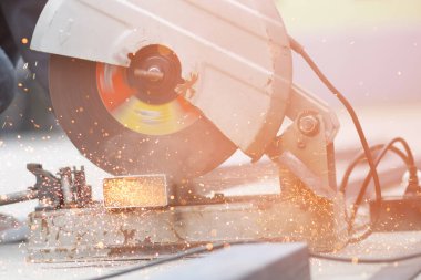 İnşaat alanında kıvılcım saçan çelik kesme makinesiyle çelik kesen bir işçi..