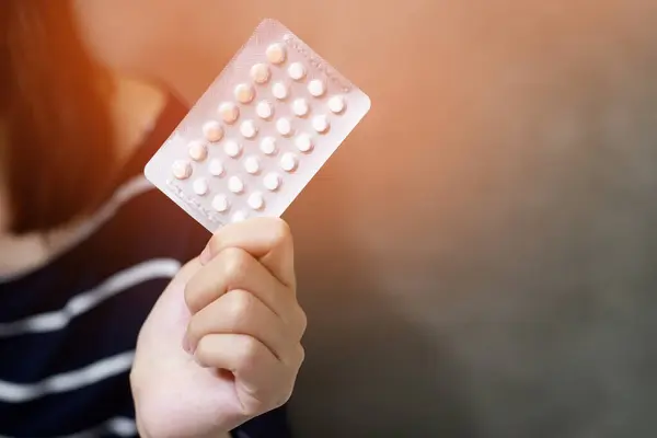 Woman hands opening birth control pills in hand. eating Contraceptive pill. Contraception reduces childbirth and pregnancy concept.